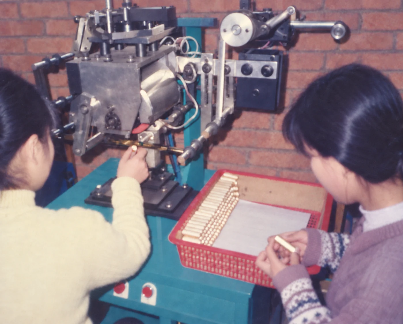 Baosheng, 1970s — two workers at a ferrule press, a tray of finished handles beside them